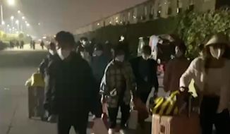 In this photo taken from video footage and released by Hangpai Xingyang, people with suitcases and bags are seen leaving from a Foxconn compound in Zhengzhou in central China&#39;s Henan Province on Saturday, Oct. 29, 2022. Workers in a Foxconn facility in the central Chinese city of Zhengzhou appear to have left the facility to avoid COVID-19 curbs, with many traveling by foot days after an unknown number of factory workers were quarantined in the facility following a virus outbreak. (Hangpai Xingyang via AP)