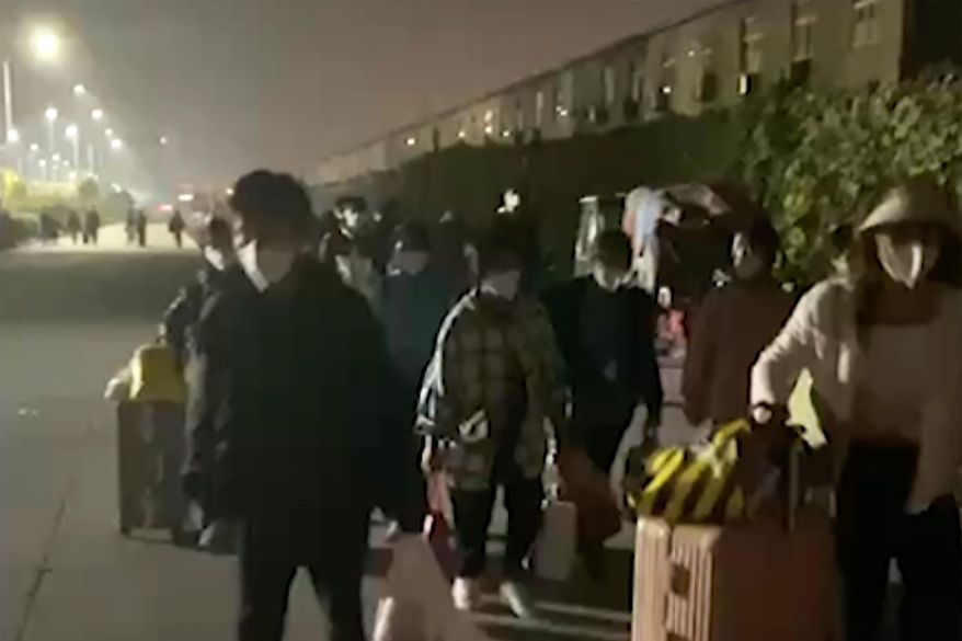 In this photo taken from video footage and released by Hangpai Xingyang, people with suitcases and bags are seen leaving from a Foxconn compound in Zhengzhou in central China&#x27;s Henan Province on Saturday, Oct. 29, 2022. Workers in a Foxconn facility in the central Chinese city of Zhengzhou appear to have left the facility to avoid COVID-19 curbs, with many traveling by foot days after an unknown number of factory workers were quarantined in the facility following a virus outbreak. (Hangpai Xingyang via AP)