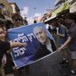 People take photo with an election campaign poster depicting former Israeli Prime Minister and Likud party leader Benjamin Netanyahu at Mahane Yehuda market in Jerusalem a day ahead of Israeli national elections, Monday, Oct. 31, 2022. Israel is holding its fifth election in under four years on Nov. 1, 2022. Hebrew on banner reads &amp;quot;Only the Likud can&amp;quot;. (AP Photo/Mahmoud Illean)