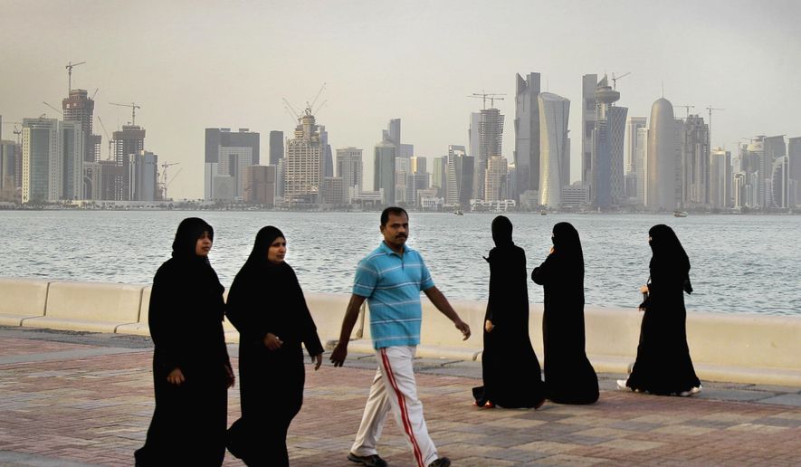 Qatari women and a man walk in front of the city skyline in Doha, Qatar, Saturday, April 7, 2012. The foreign fans descending on Doha for the 2022 FIFA World Cup will find a country where women work, hold public office and cruise in their supercars along the city&#39;s palm-lined corniche. (AP Photo/Kamran Jebreili, File)