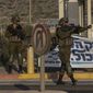 Israeli soldiers gesture to a vehicle at Tapuah Junction, next to a campaign poster for former Israeli Prime Minister Benjamin Netanyahu near the West Bank town of Nablus, Sunday, Oct. 16, 2022. (AP Photo/Tsafrir Abayov, File)