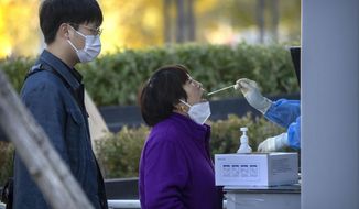 A woman has her throat swabbed for a COVID-19 test at a coronavirus testing site in Beijing, Friday, Nov. 4, 2022. Chinese stocks in Hong Kong gained Friday after the health ministry said the mainland&#x27;s severe anti-virus controls should be less costly and disruptive and a city said it would ease restrictions after access to an area around the world&#x27;s biggest iPhone factory was suspended. (AP Photo/Mark Schiefelbein)