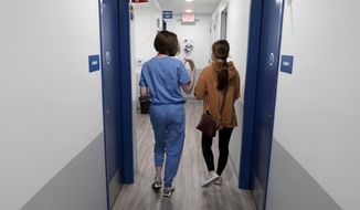 Dr. Elizabeth Brett Daily, left, walks with patient Haley Ruark after providing a medical abortion at a Planned Parenthood clinic Wednesday, Oct. 12, 2022, in Kansas City, Kan. (AP Photo/Charlie Riedel)