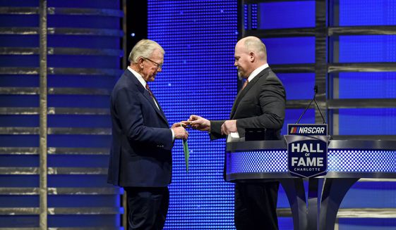 Coy Gibbs, right, presents the Hall of Fame ring to his father, NASCAR Hall of Fame inductee Joe Gibbs, during the induction ceremony in Charlotte, N.C., on Jan. 31, 2020. Coy, the vice chairman at Joe Gibbs Racing for his NFL and NASCAR Hall of Fame father, died Sunday morning, Nov. 6, 2022. He was 49. His death came just hours after his son Ty won the Xfinity Series championship. (AP Photo/Mike McCarn, File) **FILE**