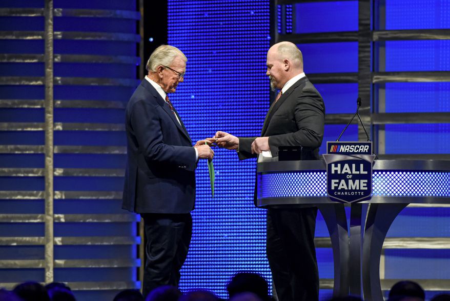 Coy Gibbs, right, presents the Hall of Fame ring to his father, NASCAR Hall of Fame inductee Joe Gibbs, during the induction ceremony in Charlotte, N.C., on Jan. 31, 2020. Coy, the vice chairman at Joe Gibbs Racing for his NFL and NASCAR Hall of Fame father, died Sunday morning, Nov. 6, 2022. He was 49. His death came just hours after his son Ty won the Xfinity Series championship. (AP Photo/Mike McCarn, File) **FILE**