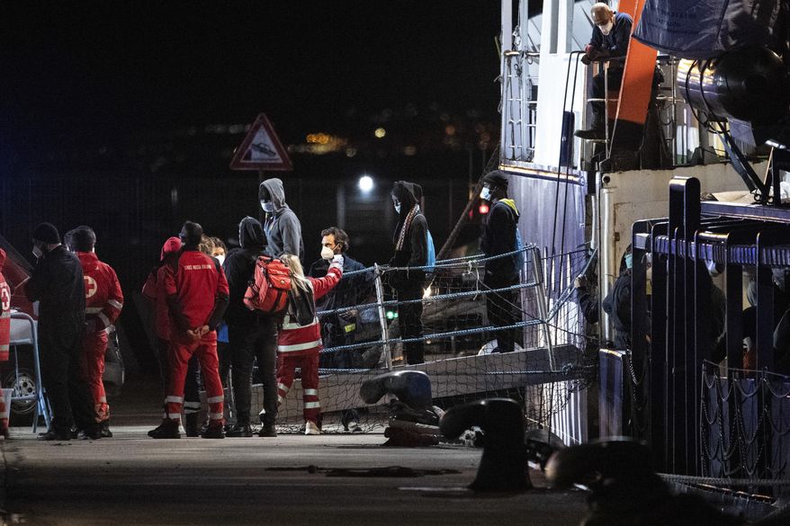 Migrants disembark from the Humanity 1 rescue ship run by the German organization SOS Humanitarian, in the port of Catania, Sicily, southern Italy, early Sunday, Nov. 6, 2022. Italy allowed the Humanity 1 rescue ship carrying over 100 migrants to enter the Sicilian port and begin disembarking minors, while refusing to respond to requests for safe harbor from three other ships carrying 900 more people in nearby waters. (AP Photo/Salvatore Cavalli)