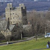 A Cornell University student walks along the campus in Ithaca, N.Y., on Dec. 16, 2021, with luggage in tow. (AP Photo/Heather Ainsworth, File) **FILE**