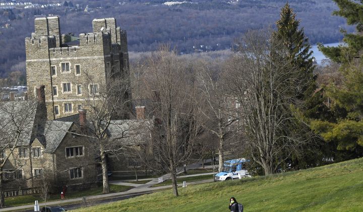 A Cornell University student walks along the campus in Ithaca, N.Y., on Dec. 16, 2021, with luggage in tow. (AP Photo/Heather Ainsworth, File) **FILE**