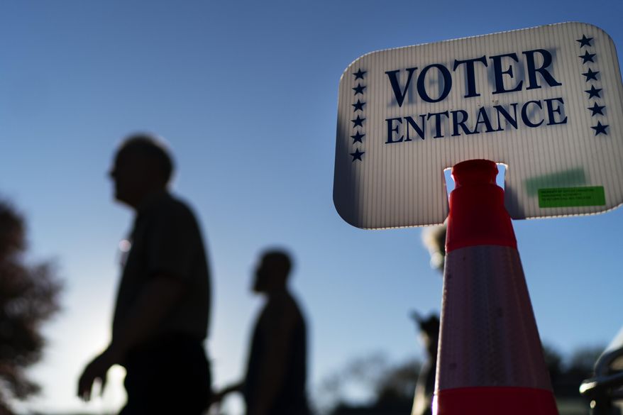 Voters pass a sign outside a polling site in Warwick, R.I., Monday, Nov. 7, 2022, after casting their ballots on the last day of early voting before the midterm election. (AP Photo/David Goldman)