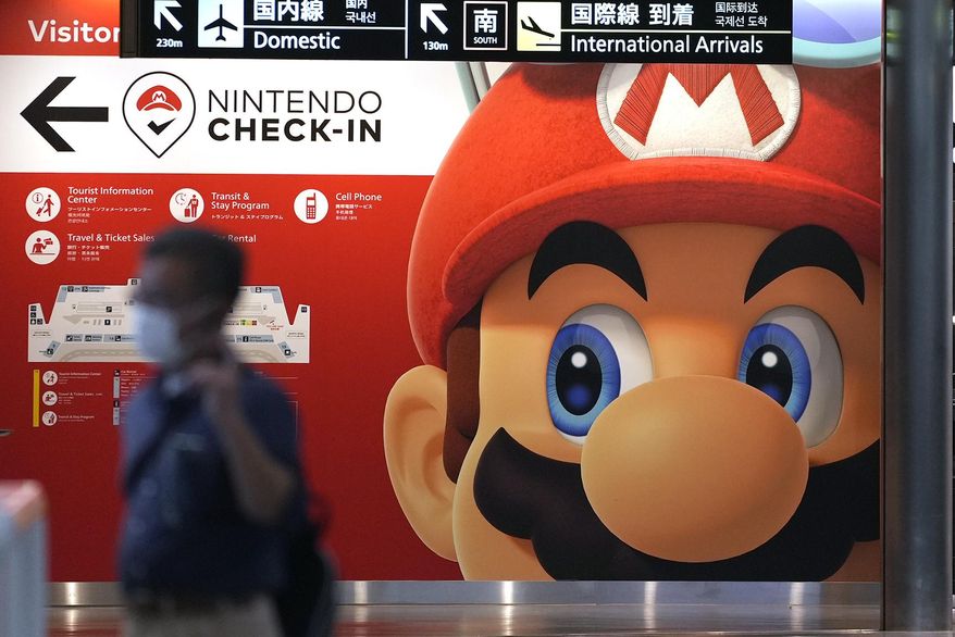 A traveler walks past an advertisement featuring a Nintendo character at Narita airport in Narita near Tokyo on June 10, 2022. Nintendo hopes to leverage a new Super Mario movie, various merchandising and theme parks to draw more people into playing its video games, President Shuntaro Furukawa said Wednesday, Nov. 9, 2022. (AP Photo/Shuji Kajiyama, File)