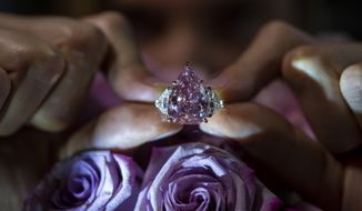 A Christie&#39;s employee displays a pink diamond called &amp;quot;The Fortune Pink&amp;quot; of 18,18 carat, during a preview at Christie&#39;s, in Geneva, Switzerland, Wednesday, Nov. 2, 2022. The pear-shaped 18-carat pink diamond is set to be sold at auction on Tuesday and is expected to fetch between $25 million and $35 million. (Martial Trezzini/Keystone via AP)