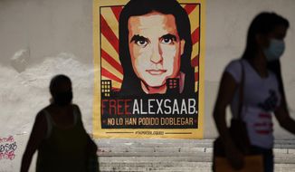 Pedestrians walk near a poster asking for the freedom of Colombian businessman and Venezuelan special envoy Alex Saab, in Caracas, Venezuela, Sept. 9, 2021. Saab’s attorneys filed a new motion on Oct. 17, 2022 to dismiss criminal charges, arguing once again that he was illegally abducted on U.S. orders while traveling as a diplomat to Iran. Saab was arrested in Cape Verde in June 2020, and extradited to the U.S to face charges in Oct. 2021. (AP Photo/Ariana Cubillos, File)