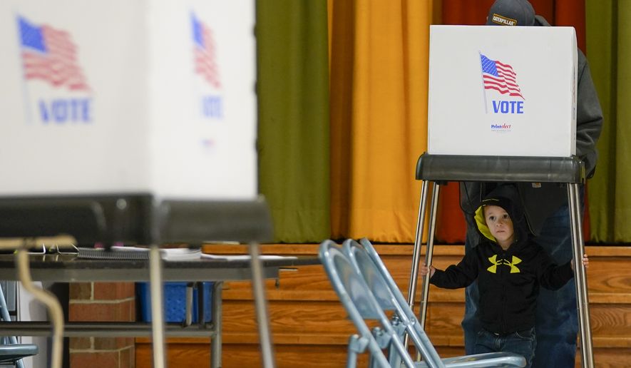 FILE - Jacob Lewis, 3, waits at a privacy booth as his grandfather, Robert Schroyer, fills out his ballot while voting at Sabillasville Elementary School, Nov. 8, 2022, in Sabillasville, Md. (AP Photo/Julio Cortez, File)