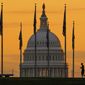 An early morning pedestrian is silhouetted against sunrise as he walks through the U.S. Flags on the National Mall and past the U.S. Capitol Building in Washington, Monday, Nov. 7, 2022. President Biden is asking Congress to hand over another $10 billion in funding to combat COVID-19 and other infectious diseases, and an additional $37.7 billion in aid to Ukraine as Congress begins debate on its next spending measure ahead of a mid-December deadline. (AP Photo/J. David Ake)