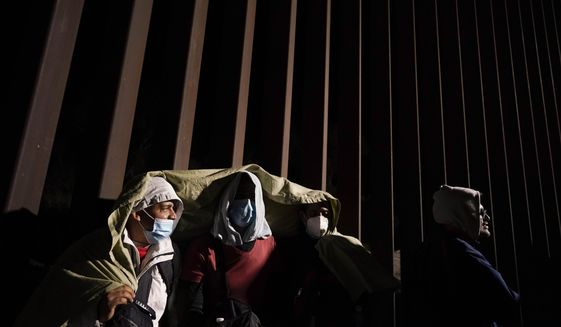 Four men from Cuba try to keep warm after crossing the border from Mexico and surrendering to authorities to apply for asylum on Nov. 3, 2022, near Yuma, Ariz. U.S. District Judge Emmet Sullivan on Tuesday, Nov. 15, ordered the Biden administration to lift Trump-era asylum restrictions that have been a cornerstone of border enforcement since the beginning of COVID-19. Sullivan ruled that Title 42 authority end immediately for families and single adults, saying it violates federal rule-making procedures. (AP Photo/Gregory Bull, File)