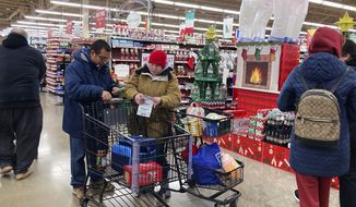 Shoppers check store coupons as they shop at a grocery store in Glenview, Ill., Saturday, Nov. 19, 2022. (AP Photo/Nam Y. Huh) ** FILE **