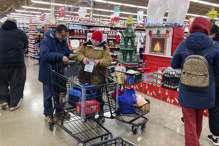 Shoppers check store coupons as they shop at a grocery store in Glenview, Ill., Saturday, Nov. 19, 2022. (AP Photo/Nam Y. Huh) ** FILE **