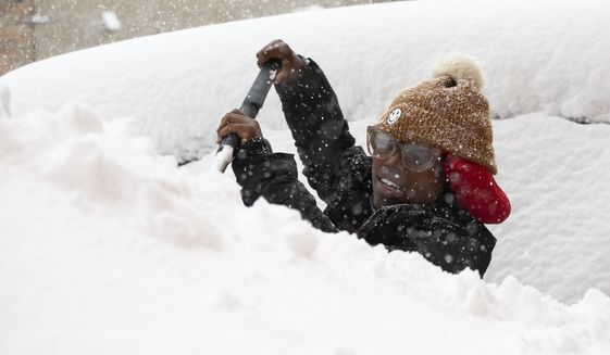 Zaria Black, 24, from Buffalo, clears off her car as snow falls Friday, Nov. 18, 2022, in Buffalo, N.Y.  A dangerous lake-effect snowstorm paralyzed parts of western and northern New York, with nearly 2 feet of snow already on the ground in some places and possibly much more on the way.  (AP Photo/Joshua Bessex)