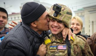 FILE - A Kherson resident kisses a Ukrainian soldier in central Kherson, Ukraine, Sunday, Nov. 13, 2022. Ukraine liberated Kherson more than one week ago, and the city’s streets are revived for the first time in many months. People no longer sit in their homes in fear of meeting the Russians. Instead, they gather in the city’s squares to recharge their phones, collect water and catch a connection to talk to their relatives. (AP Photo/Efrem Lukatsky, file)