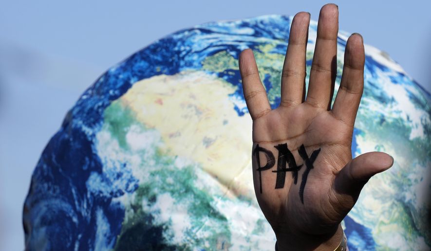 A hand reads &amp;quot;pay&amp;quot; calling for reparations for loss and damage at the COP27 U.N. Climate Summit, Friday, Nov. 18, 2022, in Sharm el-Sheikh, Egypt. (AP Photo/Peter Dejong, File)