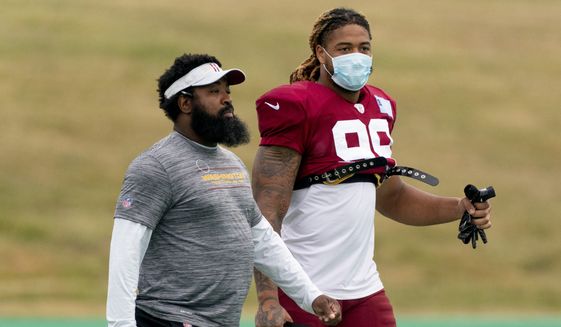 Washington Football Team defensive end Chase Young (99) speaks with defensive line coach Sam Mills III, left, as they arrive for the the team&#39;s NFL football training camp practice in Ashburn, Va., Wednesday, Aug. 4, 2021. (AP Photo/Andrew Harnik) **FILE**