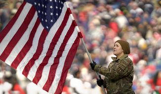 A member of the military holds an American flag during ceremonies before an NFL football game between the New York Jets and the New England Patriots, Sunday, Nov. 20, 2022, in Foxborough, Mass. (AP Photo/Steven Senne)