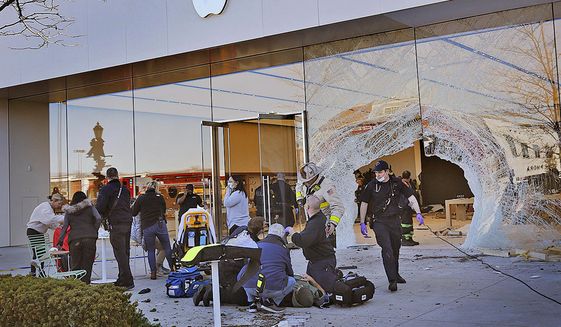 Emergency workers aid injured shoppers after an SUV drove into an Apple store, Monday, Nov. 21, 2022, in Hingham, Mass. Several people were injured in the incident, according to authorities. (Greg Derr/The Patriot Ledger via AP)