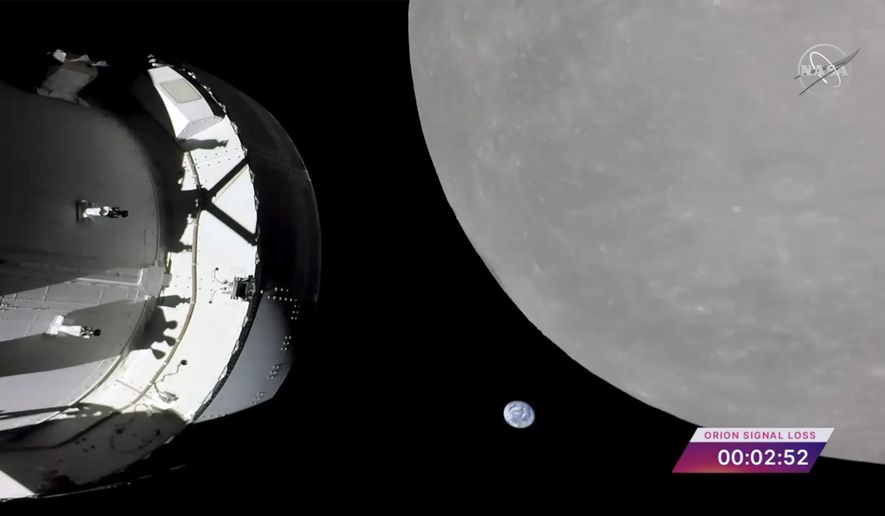 This screengrab from NASA TV shows NASA&#x27;s Orion capsule, left, nearing the moon, right, Monday, Nov. 21, 2022. At center is earth. (NASA via AP)