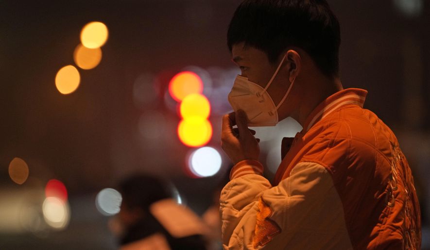 A man adjusts his mask on the street of Beijing, Sunday, Nov. 20, 2022. China on Sunday announced its first new death from COVID-19 in nearly half a year as strict new measures are imposed in Beijing and across the country to ward against new outbreaks. (AP Photo/Ng Han Guan)