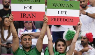Iranian soccer fans hold up signs reading Woman Life Freedom and Freedom For Iran, prior to the World Cup group B soccer match between England and Iran at the Khalifa International Stadium in in Doha, Qatar, Monday, Nov. 21, 2022. (AP Photo/Alessandra Tarantino)