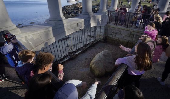 Schoolchildren gather around Plymouth Rock, Tuesday, Nov. 22, 2022, in Plymouth, Mass. Tourists annually make a Thanksgiving trek to the rock along the harbor, the symbolic spot where the Pilgrims landed more than 400 years ago. (AP Photo/Charles Krupa)