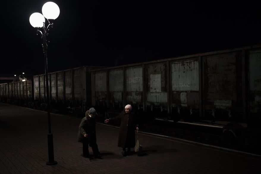 Two elderly Ukrainian women walk towards the Kherson-Kyiv train at the Kherson railway station, southern Ukraine, Monday, Nov. 21, 2022. Ukrainian authorities are evacuating civilians from recently liberated sections of the Kherson and Mykolaiv regions, fearing that a lack of heat, power and water due to Russian shelling will make conditions too unlivable this winter. The move came as rolling blackouts on Monday plagued most of the country. (AP Photo/Bernat Armangue)