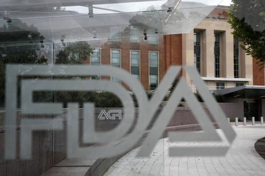 The U.S. Food and Drug Administration building stands behind an FDA logo at a bus stop on the agency's campus on Aug. 2, 2018, in Silver Spring, Md. The U.S. health regulators on Tuesday, Nov. 22, 2022, have approved the first gene therapy for hemophilia, a $3.5 million treatment that paves the way for new options in treating the blood-clotting disorder. (AP Photo/Jacquelyn Martin, File)