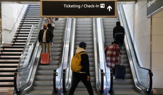Travelers ride escalators in a terminal at Ronald Reagan Washington National Airport in Arlington, Va., Wednesday, Nov. 23, 2022. (AP Photo/Patrick Semansky)