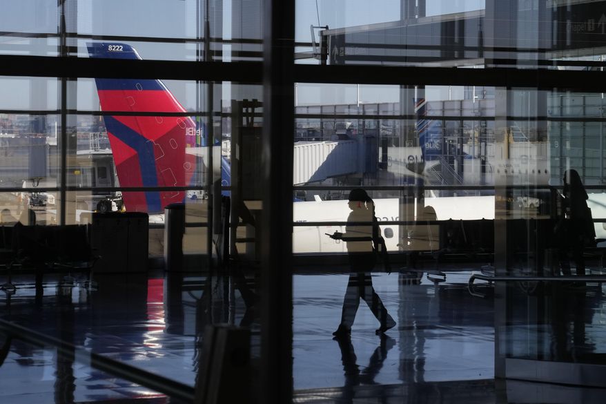 A traveler is reflected in window while walking on a concourse at Ronald Reagan Washington National Airport in Arlington, Va., Wednesday, Nov. 23, 2022. (AP Photo/Patrick Semansky)