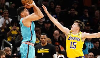 Phoenix Suns&#39; Devin Booker shoots a three pointer against Los Angeles Lakers&#39; Austin Reaves (15) during the first half of an NBA basketball game in Phoenix, Tuesday, Nov. 22, 2022. (AP Photo/Darryl Webb)