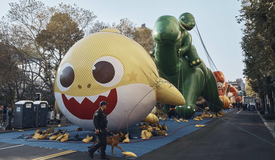Police walk by inflated helium balloons of Baby Shark and Sinclair&#39;s Dino on Wednesday, Nov. 23, 2022, in New York, as the balloons are readied for the Macy&#39;s Thanksgiving Day Parade on Thursday. (AP Photo/Andres Kudacki)