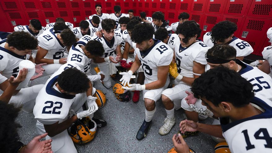 Crestwood High School football player Adam Berry (19) leads a muslim prayer before a game in Melvindale, Mich., Friday, Sept. 23, 2022. At Crestwood High School, where most of the football team is Muslim, the entire team gathers before practices and games to pray on one knee. (AP Photo/Paul Sancya)