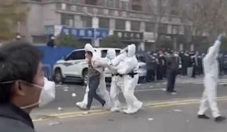 In this photo provided Nov 23, 2022, security personnel in protective clothing were seen taking away a person during protest at the factory compound operated by Foxconn Technology Group who runs the world&#x27;s biggest Apple iPhone factory in Zhengzhou in central China&#x27;s Henan province. Employees at the world&#x27;s biggest Apple iPhone factory were beaten and detained in protests over pay amid anti-virus controls, according to witnesses and videos on social media Wednesday, as tensions mount over Chinese efforts to combat a renewed rise in infections. (AP)