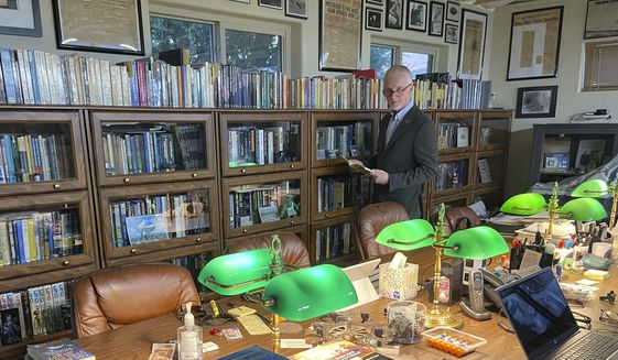 In this photo provided by David Marler, he poses on Nov. 13, 2022, in his Rio Rancho, N.M., home library filled with books and newspaper clippings related to UFO case files spanning decades A group of historians and archivists have announced plans to open a new national archive in the Albuquerque area focusing on unidentified aerial phenomenon that will be led by author and researcher David Marler. (David Marler via AP)