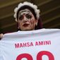 A woman holds a jersey with the name of Mahsa Amini, a woman who died while in police custody in Iran at the age of 22, as she takes her place in the stands ahead of the World Cup group B soccer match between Wales and Iran, at the Ahmad Bin Ali Stadium in Al Rayyan, Qatar, Friday, Nov. 25, 2022. (AP Photo/Pavel Golovkin)