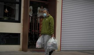 A man carries his purchased groceries past the closed shops as part of COVID-19 controls in Beijing, Thursday, Nov. 24, 2022. China is expanding lockdowns, including in a central city where factory workers clashed this week with police, as its number of COVID-19 cases hit a daily record. (AP Photo/Andy Wong)