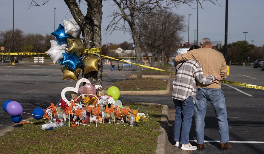 Debbie, left, and Chet Barnett place flowers at a memorial outside of the Chesapeake, Va., Walmart on Thursday, Nov. 24, 2022.  Andre Bing, a Walmart manager, opened fire on fellow employees in the break room of the Virginia store, killing six people in the country’s second high-profile mass shooting in four days, police and witnesses said Wednesday. (Billy Schuerman/The Virginian-Pilot via AP)