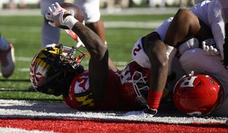 Maryland running back Roman Hemby (24) raises the football after he scored a touchdown during the first half of an NCAA college football game next to Rutgers defensive back Avery Young (2), Saturday, Nov. 26, 2022, in College Park, Md. (AP Photo/Nick Wass)