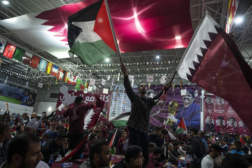 Palestinian soccer fans wave Qatari and Palestinian flags as they watch a live broadcast of the 2022 World Cup opening match between Qatar and Ecuador, at a covered gymnasium in Gaza City, on Nov. 20, 2022. For a brief moment after Saudi Arabia&#x27;s Salem Aldawsari fired a soccer ball from just inside the penalty box into the back of the net to seal a win against Argentina, Arabs across the divided Middle East found something to celebrate. (AP Photo/Fatima Shbair, File)