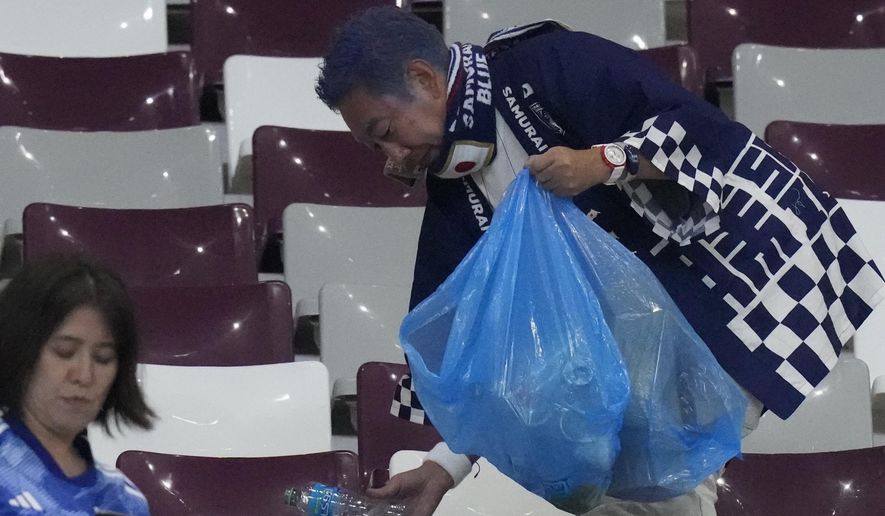 Japan supporters clean the stands at the end of the World Cup group E soccer match between Germany and Japan, at the Khalifa International Stadium in Doha, Qatar, Wednesday, Nov. 23, 2022. Japan won 2-1.(AP Photo/Eugene Hoshiko)