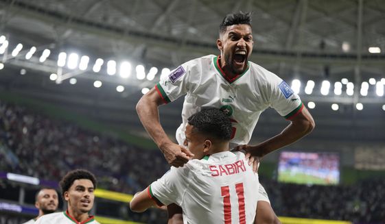 Morocco&#39;s Yahya Jabrane, top, celebrates with Abdelhamid Sabiri (11) after Sabiri scored a goal during the World Cup group F soccer match between Belgium and Morocco, at the Al Thumama Stadium in Doha, Qatar, Sunday, Nov. 27, 2022. (AP Photo/Frank Augstein)