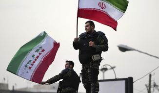 Two anti-riot police officers wave the Iranian flags during a street celebration after Iran defeated Wales in Qatar&#39;s World Cup, at Sadeghieh Sq. in Tehran, Iran, Friday, Nov. 25, 2022. Iran&#39;s political turmoil has cast a shadow over Iran&#39;s matches at the World Cup, spurring tension between those who back the team and those who accuse players of not doing enough to support the protests that started Sept. 16 over the death of a 22-year-old woman in the custody of the morality police. (AP Photo/Vahid Salemi)