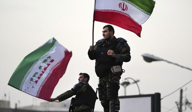 Two anti-riot police officers wave the Iranian flags during a street celebration after Iran defeated Wales in Qatar&#x27;s World Cup, at Sadeghieh Sq. in Tehran, Iran, Friday, Nov. 25, 2022. Iran&#x27;s political turmoil has cast a shadow over Iran&#x27;s matches at the World Cup, spurring tension between those who back the team and those who accuse players of not doing enough to support the protests that started Sept. 16 over the death of a 22-year-old woman in the custody of the morality police. (AP Photo/Vahid Salemi)