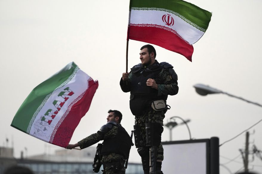 Two anti-riot police officers wave the Iranian flags during a street celebration after Iran defeated Wales in Qatar&#x27;s World Cup, at Sadeghieh Sq. in Tehran, Iran, Friday, Nov. 25, 2022. Iran&#x27;s political turmoil has cast a shadow over Iran&#x27;s matches at the World Cup, spurring tension between those who back the team and those who accuse players of not doing enough to support the protests that started Sept. 16 over the death of a 22-year-old woman in the custody of the morality police. (AP Photo/Vahid Salemi)